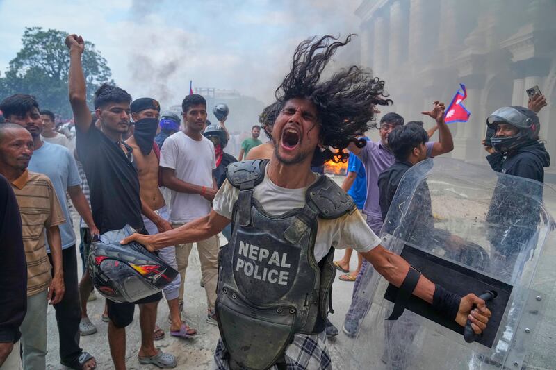 A protester wearing equipment taken from a policeman shouts slogans at the Singha Durbar, the seat of Nepal's government's various ministries and offices during a protest against social media ban and corruption in Kathmandu, Nepal, Sept. 9, 2025.